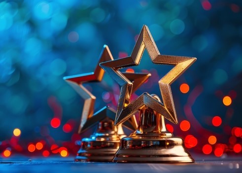 Two Gold Star Trophies on Blue Background With Red Confetti